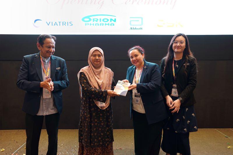 Datin Dr Mariani Ahmad Nizaruddin (2nd from right) presenting a copy of the Provisionally Registered Pharmacist Handbook to N