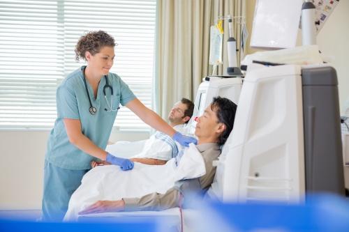 Nurse attending to man undergoing dialysis